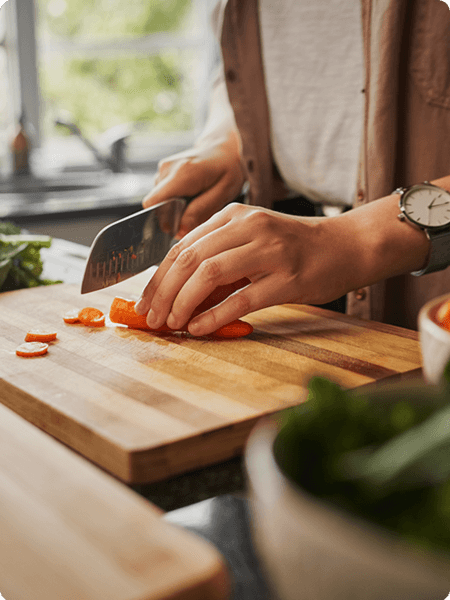 Chopping some carrots on a striped wooden cutting board