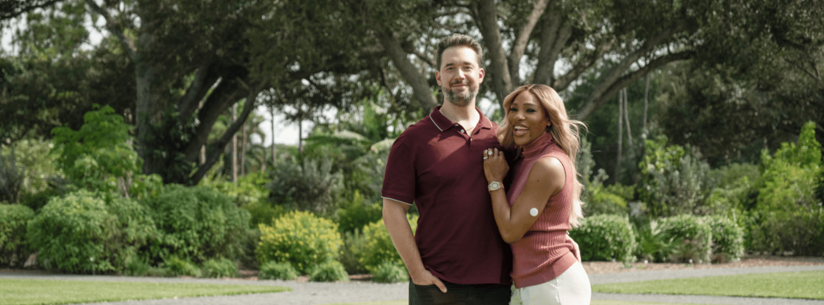 A photograph of Serena Williams and Alexis Ohanian standing together in a grassy field. 