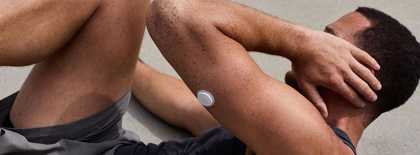 Man doing sit-ups wearing a glucose monitor