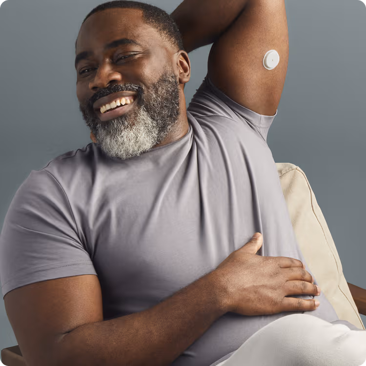 A smiling man wearing a biosensor