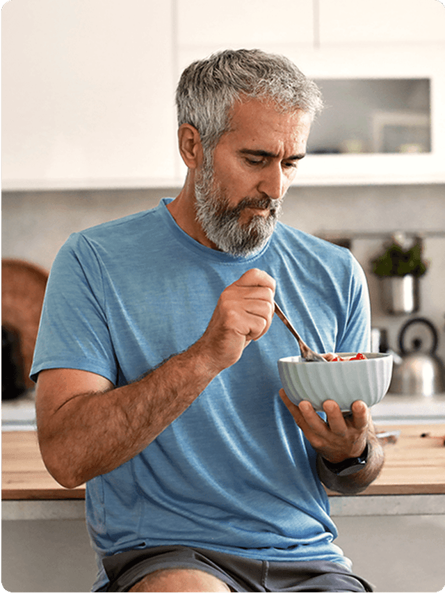 Man in blue shirt eating a bowl of food